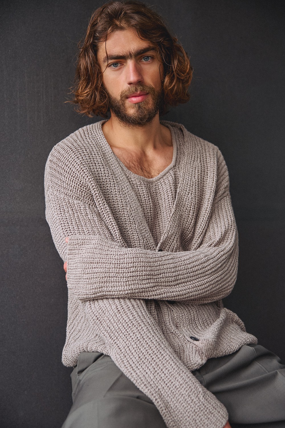 Swan Ayada in a beige knit sweater, seated against dark backdrop